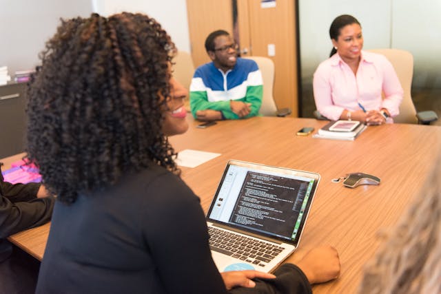 A group of Black professionals meet around an office table