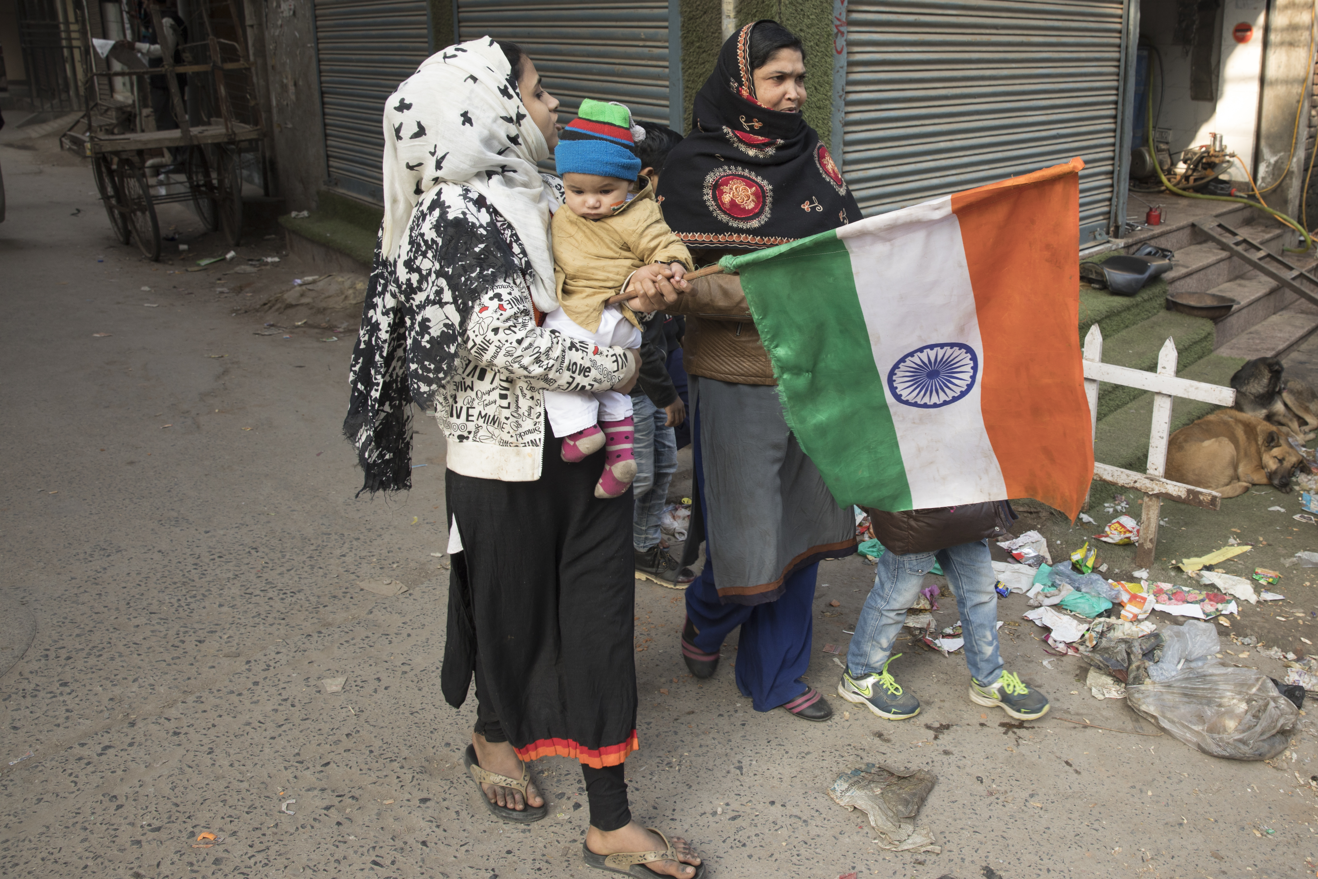 Two women with small children. One is carrying an Indian flag. 